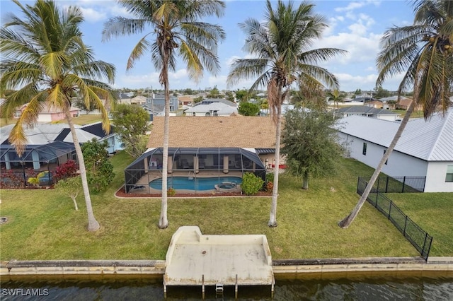 rear view of house with a yard, a water view, and a lanai