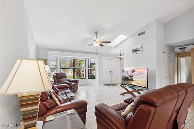 living room featuring ceiling fan with notable chandelier, light tile patterned flooring, and vaulted ceiling