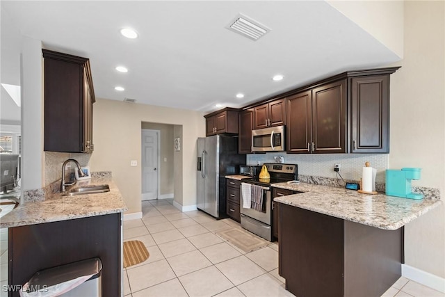 kitchen with kitchen peninsula, sink, light tile patterned floors, and appliances with stainless steel finishes