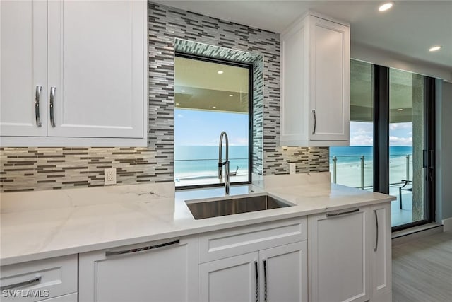 kitchen featuring white cabinets, a water view, and light stone countertops