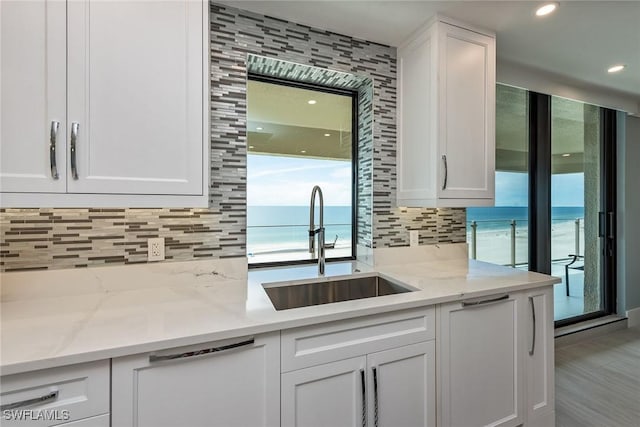 kitchen with white cabinets, light stone counters, and a water view