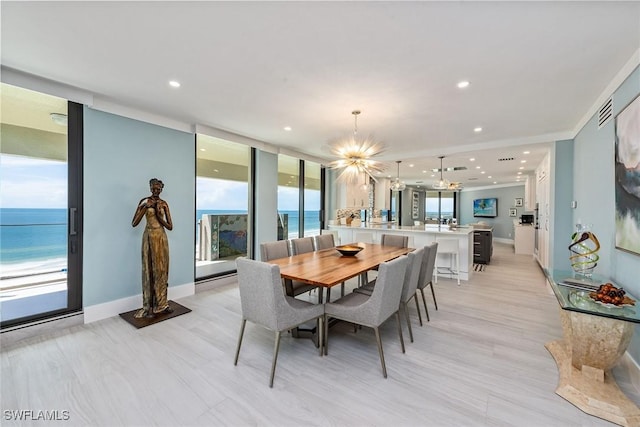 dining area featuring a notable chandelier, a water view, a wall of windows, and a wealth of natural light