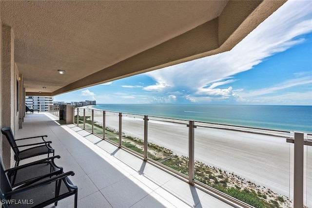 balcony featuring a view of the beach and a water view