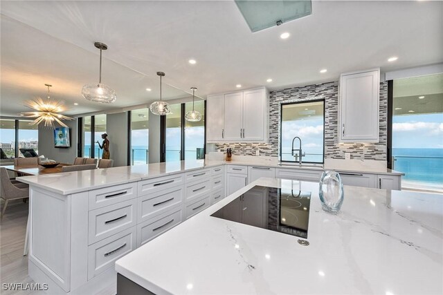 kitchen with sink, a water view, white cabinetry, and black electric cooktop