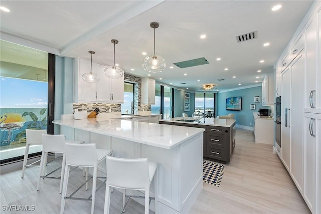 kitchen featuring decorative backsplash, white cabinetry, kitchen peninsula, and hanging light fixtures