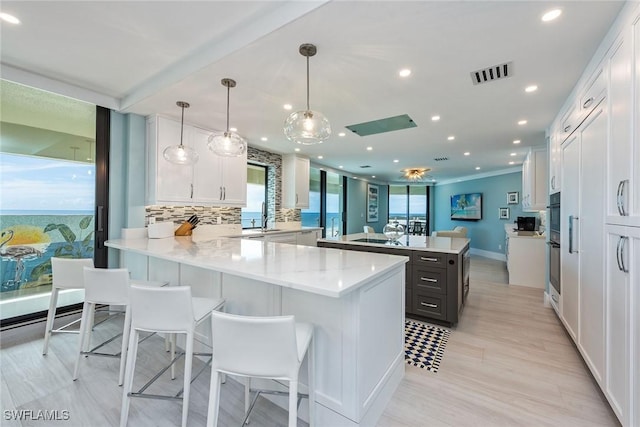 kitchen with decorative light fixtures, white cabinetry, kitchen peninsula, and tasteful backsplash