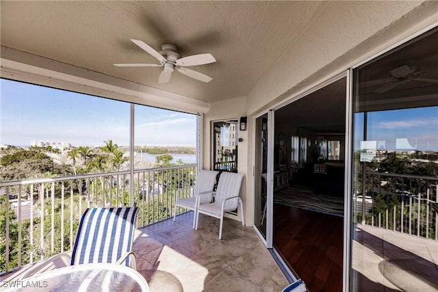 sunroom / solarium featuring a water view and ceiling fan