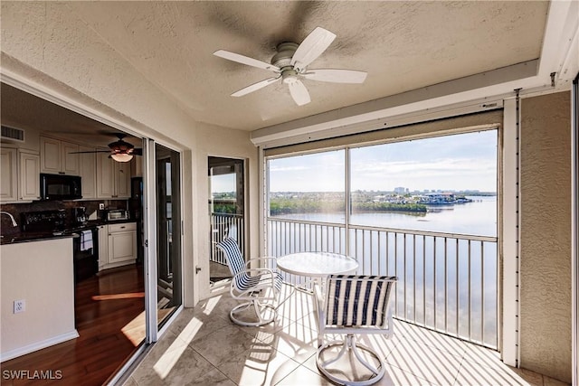 sunroom / solarium featuring a water view and ceiling fan