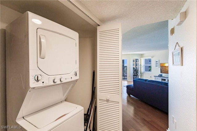 laundry area featuring a textured ceiling, dark hardwood / wood-style flooring, and stacked washer / dryer