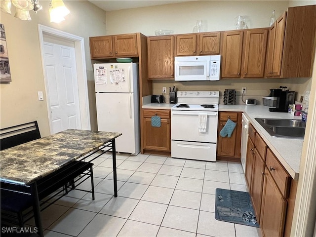 kitchen featuring light tile patterned floors, white appliances, and sink