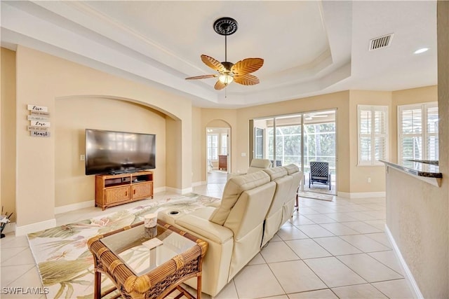 tiled living room featuring a tray ceiling and ceiling fan