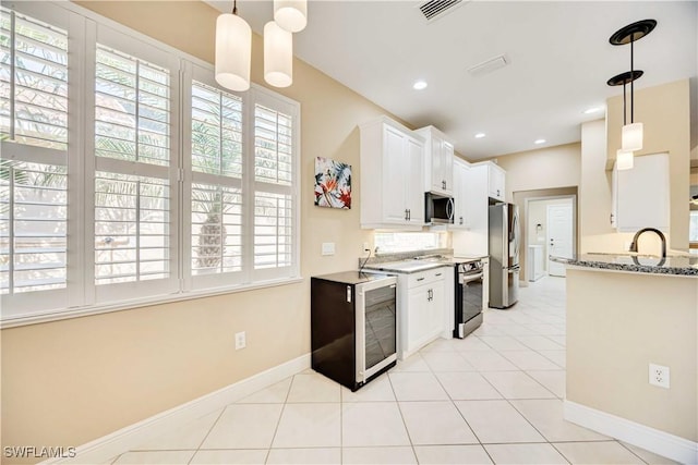 kitchen with tasteful backsplash, light stone counters, stainless steel appliances, light tile patterned floors, and white cabinets