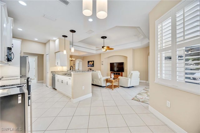 kitchen with white cabinets, ceiling fan, light stone countertops, a tray ceiling, and decorative light fixtures