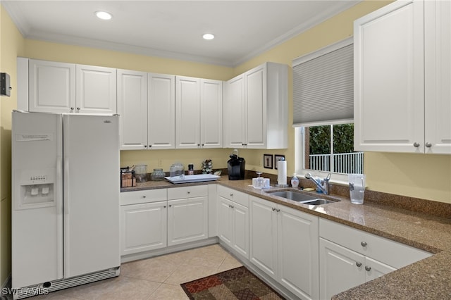 kitchen with white refrigerator with ice dispenser, white cabinets, crown molding, sink, and light tile patterned floors