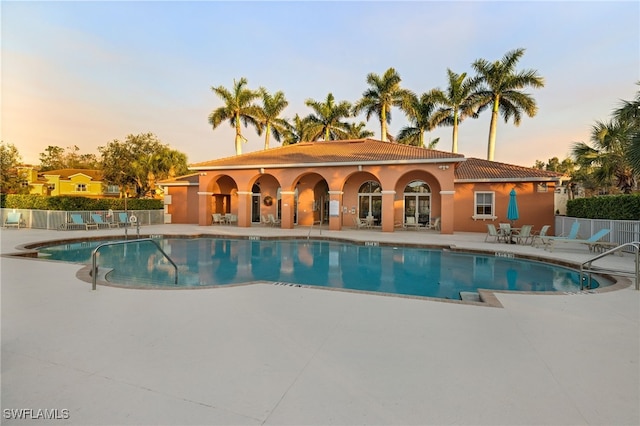 pool at dusk with a patio area