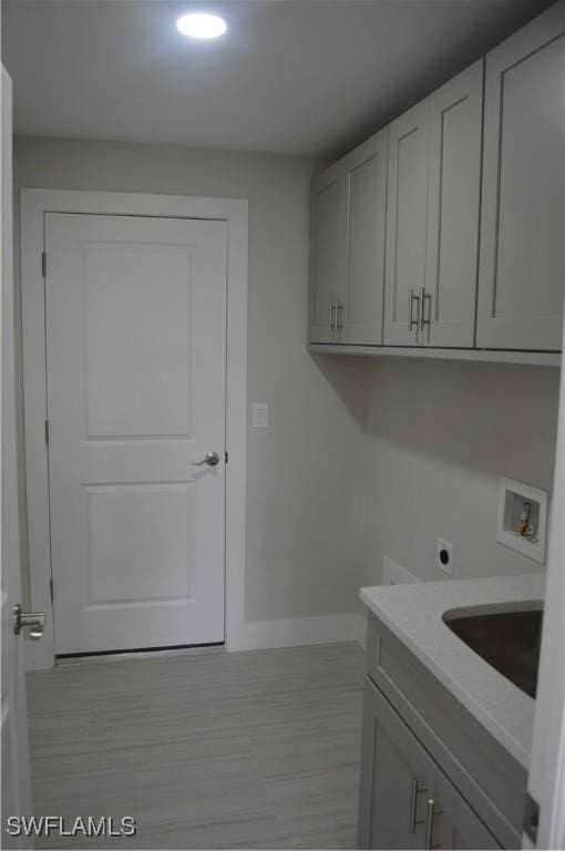 washroom featuring electric dryer hookup, cabinets, sink, and washer hookup