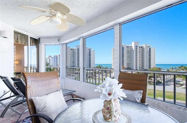 sunroom with ceiling fan, a water view, and a healthy amount of sunlight