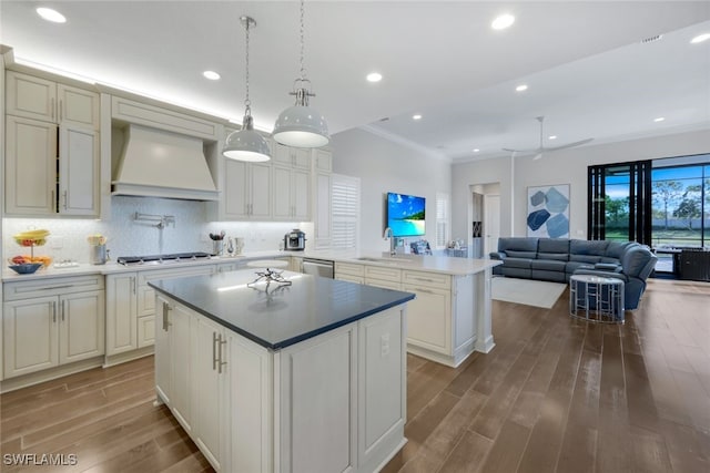 kitchen with kitchen peninsula, premium range hood, stainless steel appliances, sink, and a center island