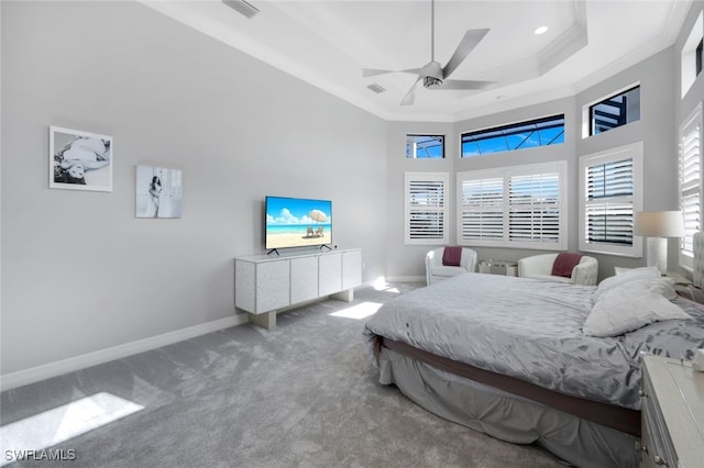 carpeted bedroom featuring a high ceiling, a tray ceiling, ceiling fan, and ornamental molding