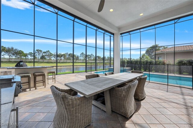 view of patio featuring ceiling fan, exterior kitchen, a water view, a fenced in pool, and an outdoor bar