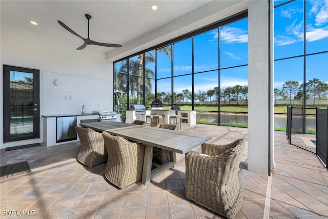 sunroom / solarium with ceiling fan, sink, and a water view