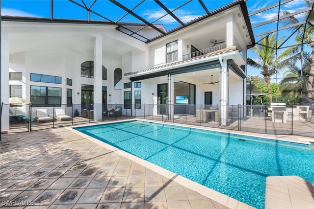 rear view of property with a balcony, glass enclosure, ceiling fan, and a patio area