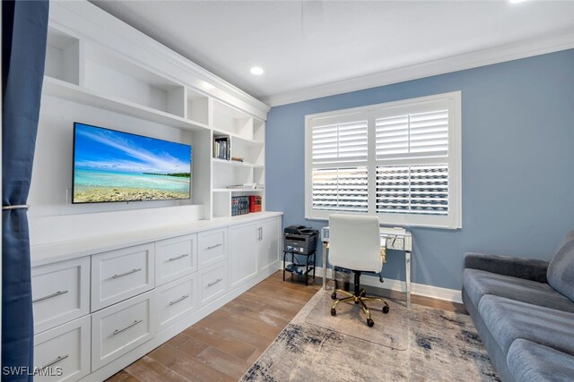 home office with light hardwood / wood-style floors, built in features, and crown molding