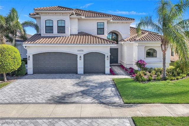 mediterranean / spanish home featuring a garage and a front lawn