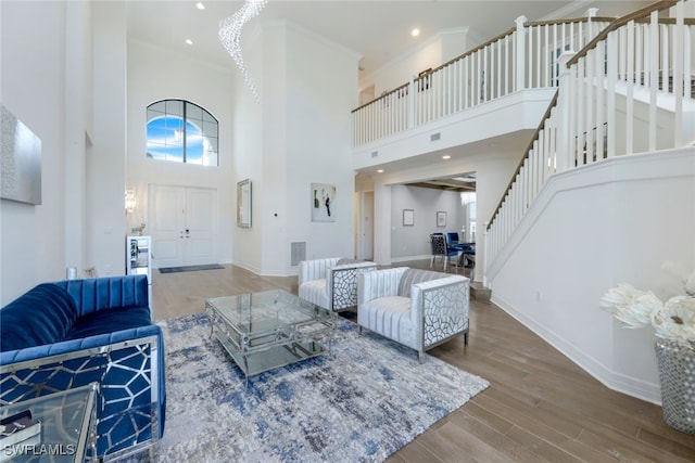 living room with hardwood / wood-style floors, a towering ceiling, and ornamental molding