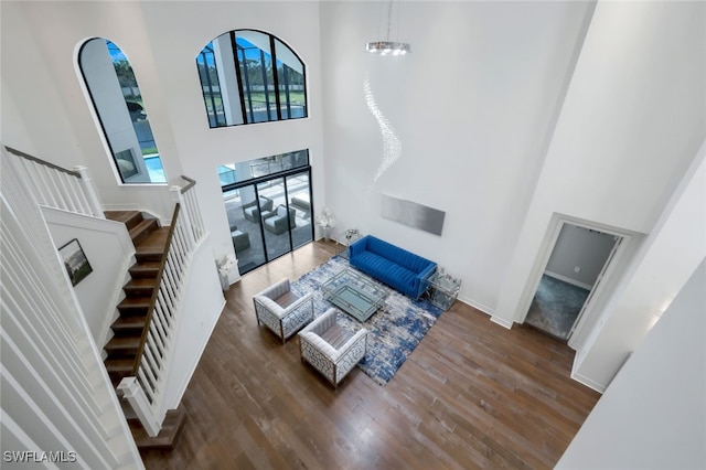 living room with dark wood-type flooring, a high ceiling, and an inviting chandelier