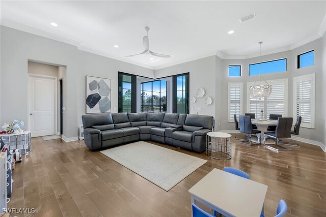 living room featuring hardwood / wood-style floors, ceiling fan with notable chandelier, and ornamental molding