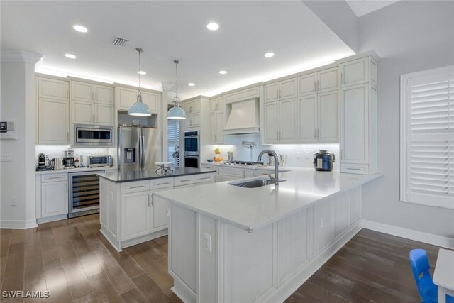 kitchen with sink, stainless steel appliances, wine cooler, pendant lighting, and custom range hood