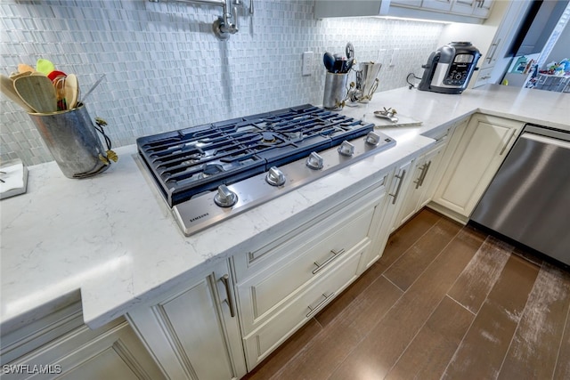 kitchen with decorative backsplash, stainless steel appliances, and light stone countertops