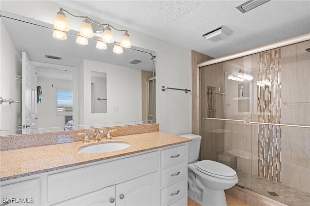 bathroom featuring toilet, a textured ceiling, a shower with shower door, and vanity