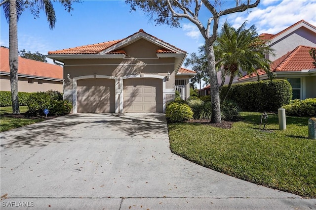 mediterranean / spanish house with a garage, a tiled roof, concrete driveway, stucco siding, and a front lawn