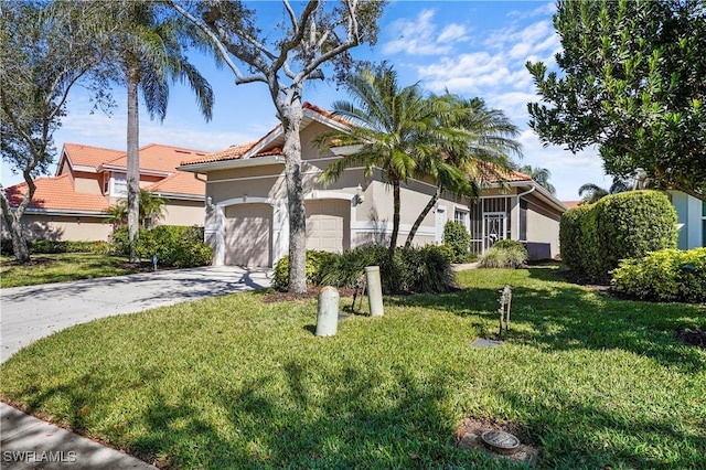 mediterranean / spanish home with driveway, a garage, a tile roof, a front lawn, and stucco siding