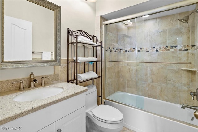 bathroom with combined bath / shower with glass door, vanity, and toilet