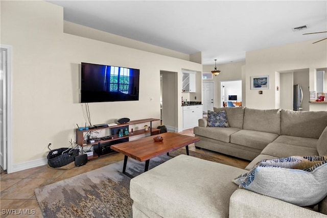 living room featuring light tile patterned floors, visible vents, and baseboards