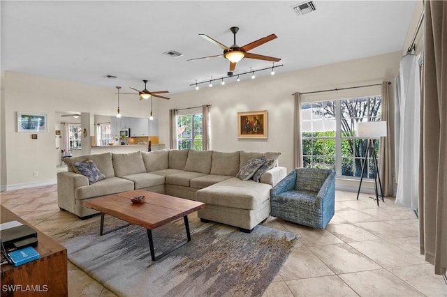 living room featuring a ceiling fan, track lighting, light tile patterned floors, and baseboards