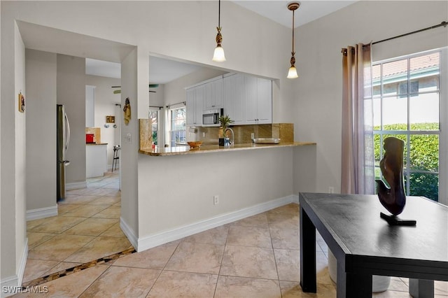 kitchen featuring stainless steel appliances, white cabinetry, decorative backsplash, pendant lighting, and baseboards