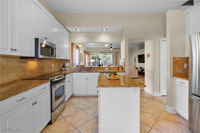 kitchen featuring stainless steel appliances, a sink, a center island, decorative backsplash, and light tile patterned floors
