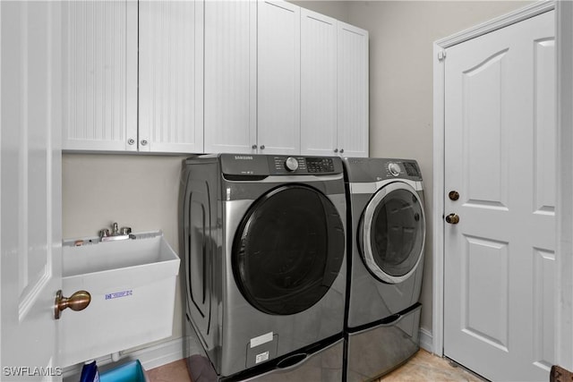 clothes washing area with cabinet space, a sink, and washing machine and clothes dryer