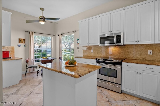 kitchen with appliances with stainless steel finishes, light tile patterned floors, decorative backsplash, and ceiling fan