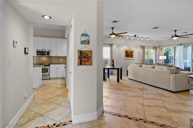 living room featuring light tile patterned floors, baseboards, visible vents, and a ceiling fan