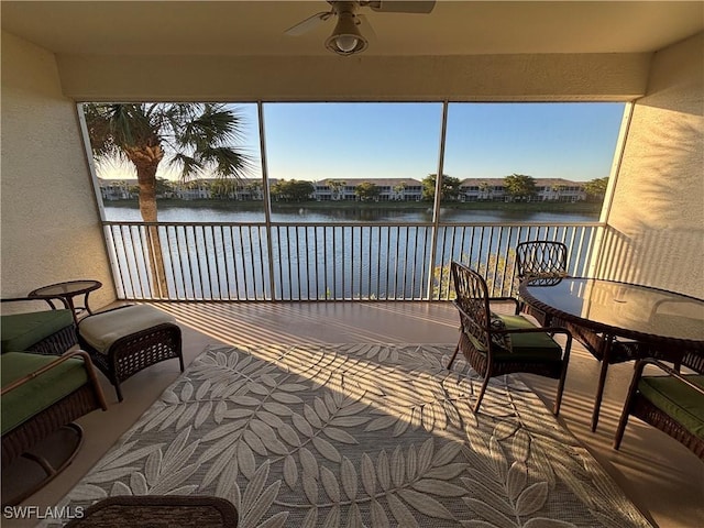 sunroom with a water view and ceiling fan