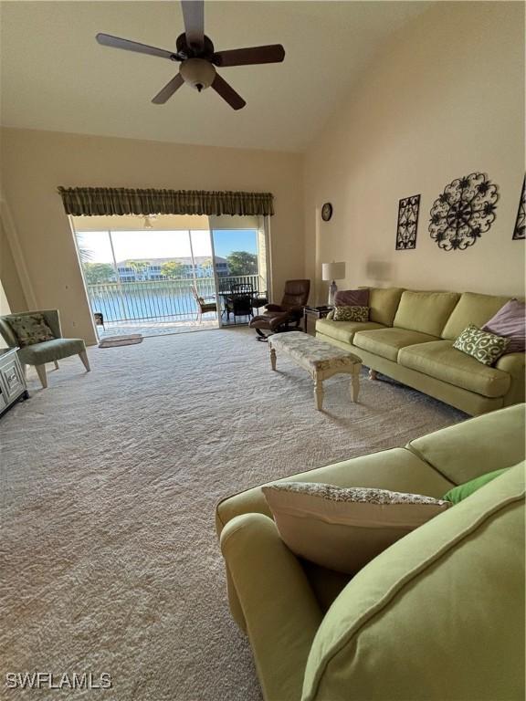 carpeted living room with a water view, vaulted ceiling, ceiling fan, and a healthy amount of sunlight