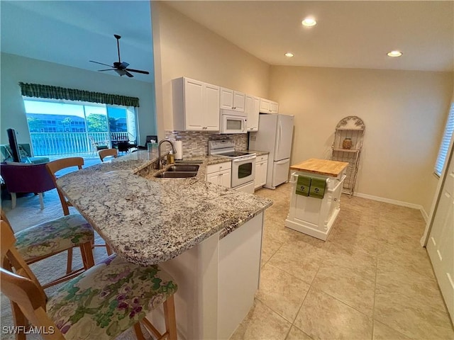 kitchen featuring white appliances, sink, kitchen peninsula, a kitchen bar, and butcher block counters