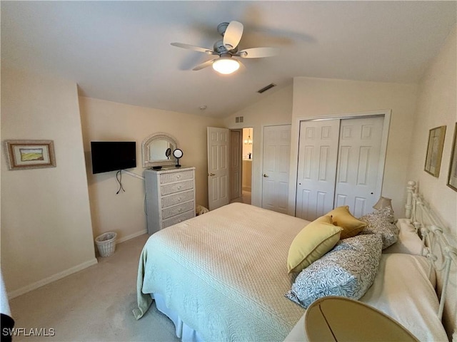 bedroom with two closets, light colored carpet, vaulted ceiling, and ceiling fan