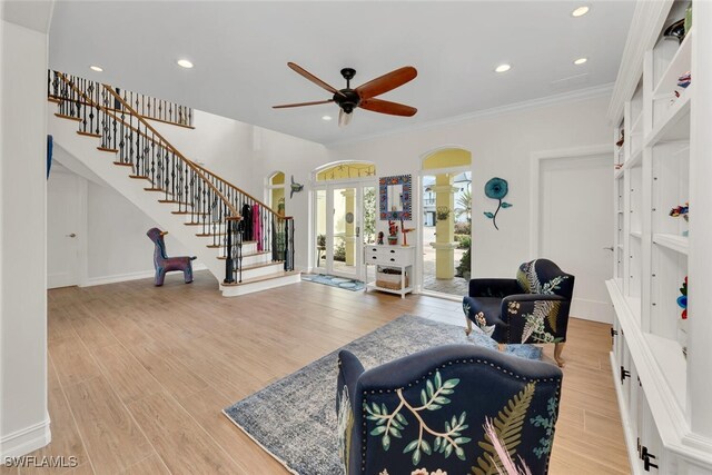 living room with light wood-type flooring, ceiling fan, and crown molding