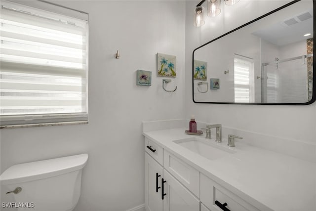 bathroom featuring a shower with door, vanity, and toilet